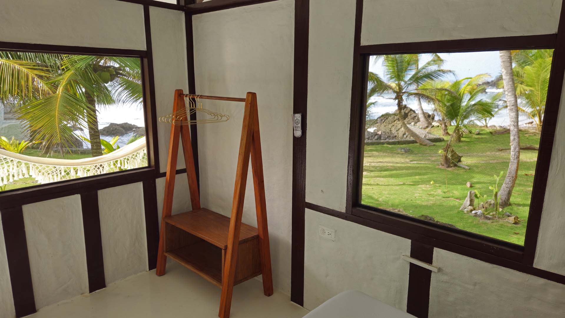 Bungalow Interior Detail Minimalist bungalow interior with wooden storage rack and palm tree views at Brisa Bahía.