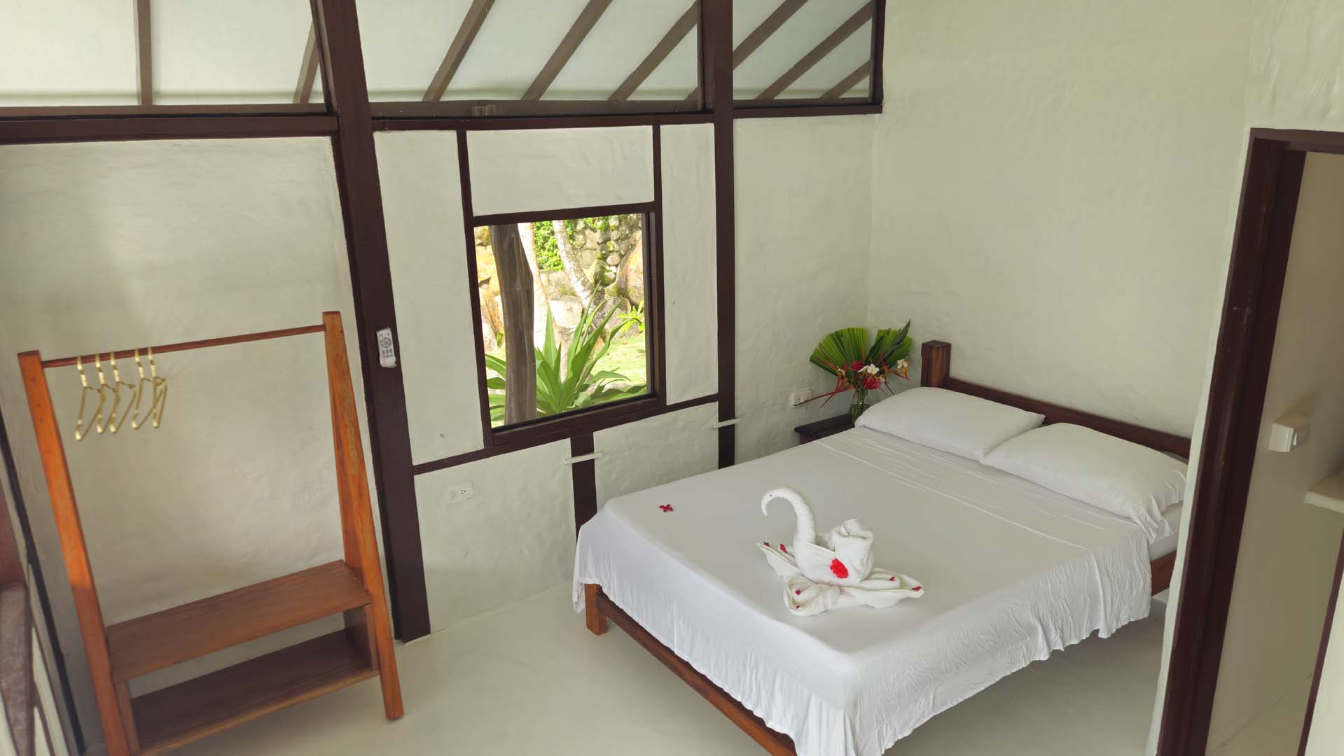Bungalow Bedroom Bright bungalow bedroom with white linens, tropical accents, and garden views at Brisa Bahía.
