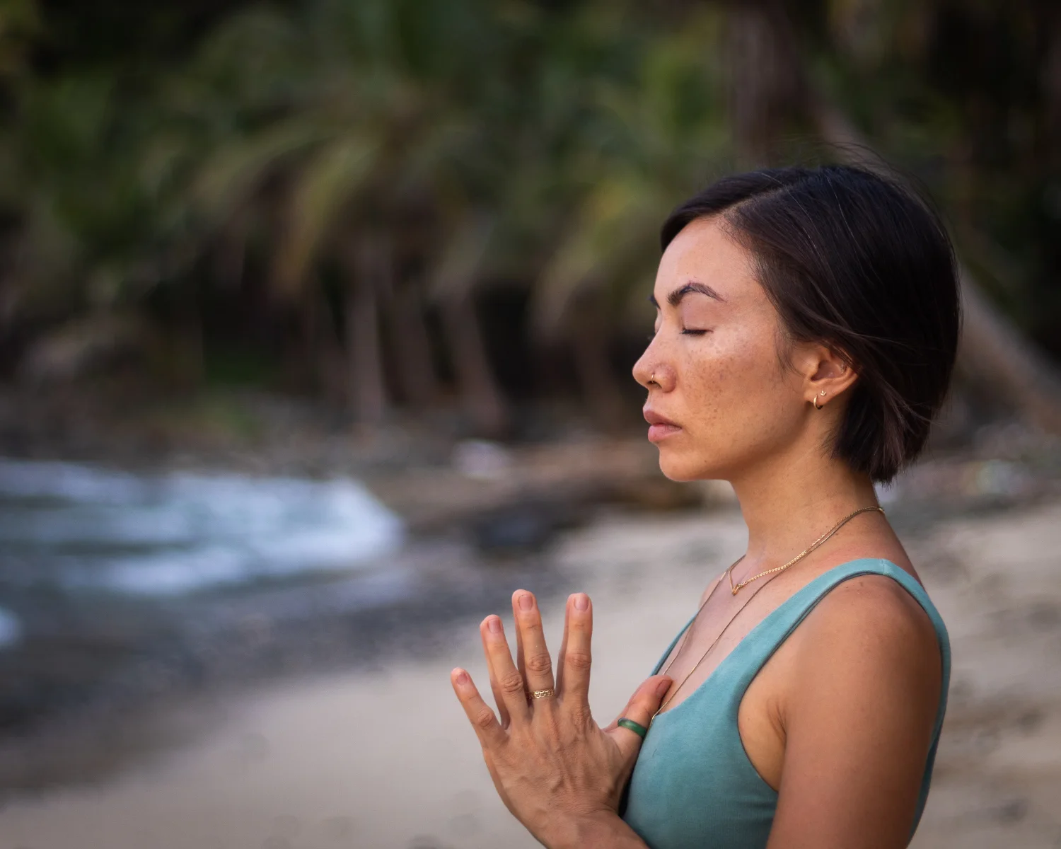 Person practicing meditation on the beach with ocean waves in the background.